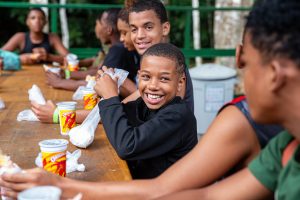 Menino sorrindo sentado à mesa na Reserva Biológica do Tinguá