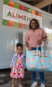 Mãe e filha com sacola de alimentos do Banco de Alimentos da Cidade de Deus